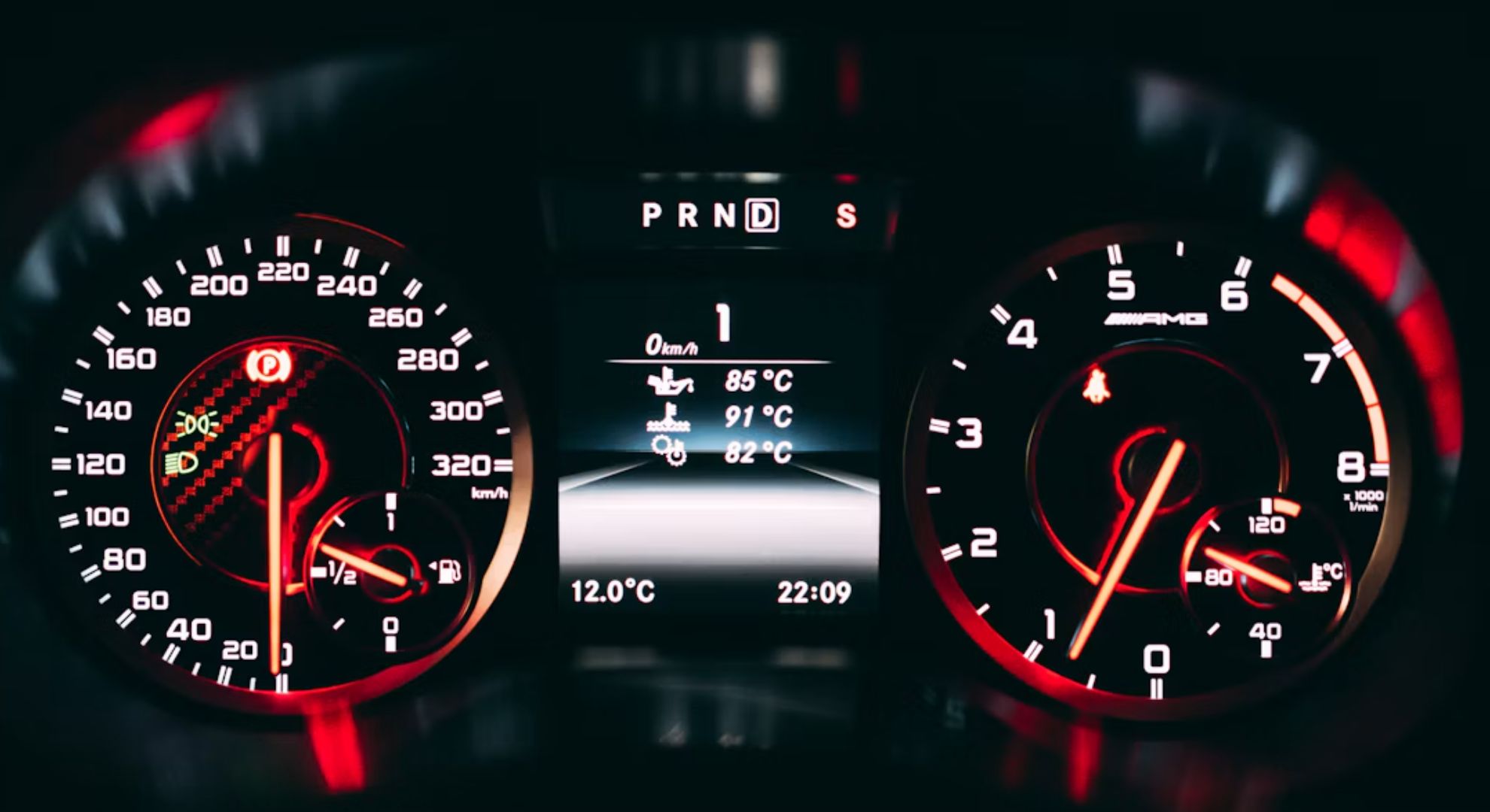 Illuminated car dashboard showing the speedometer, rev counter and engine temperature readings