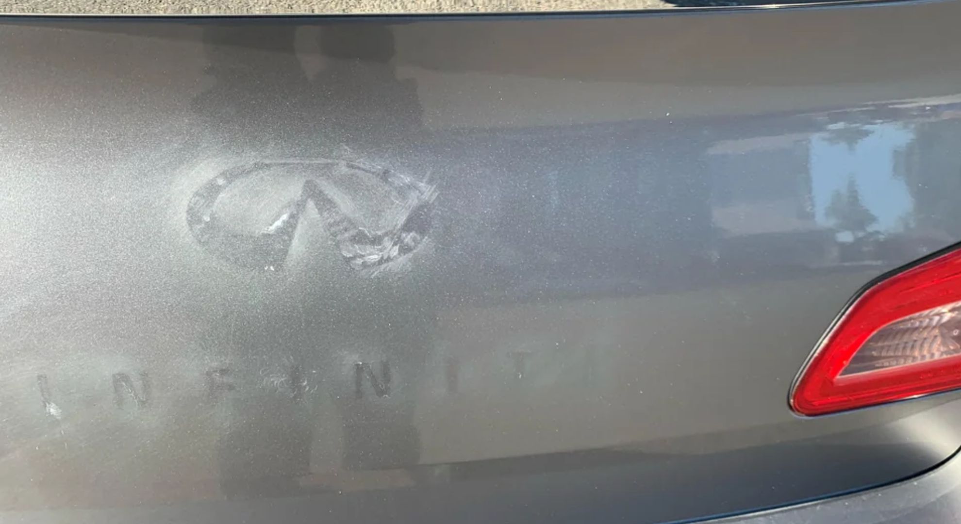 A debadging attempt on an Infiniti leaving glue residue.