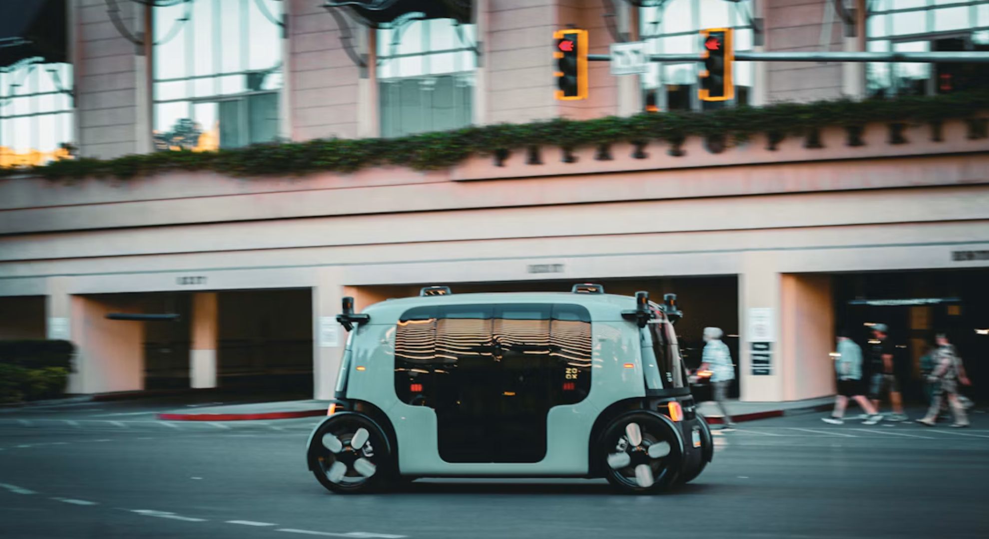 A driverless robotaxi crossing a city junction as pedestrians walk past